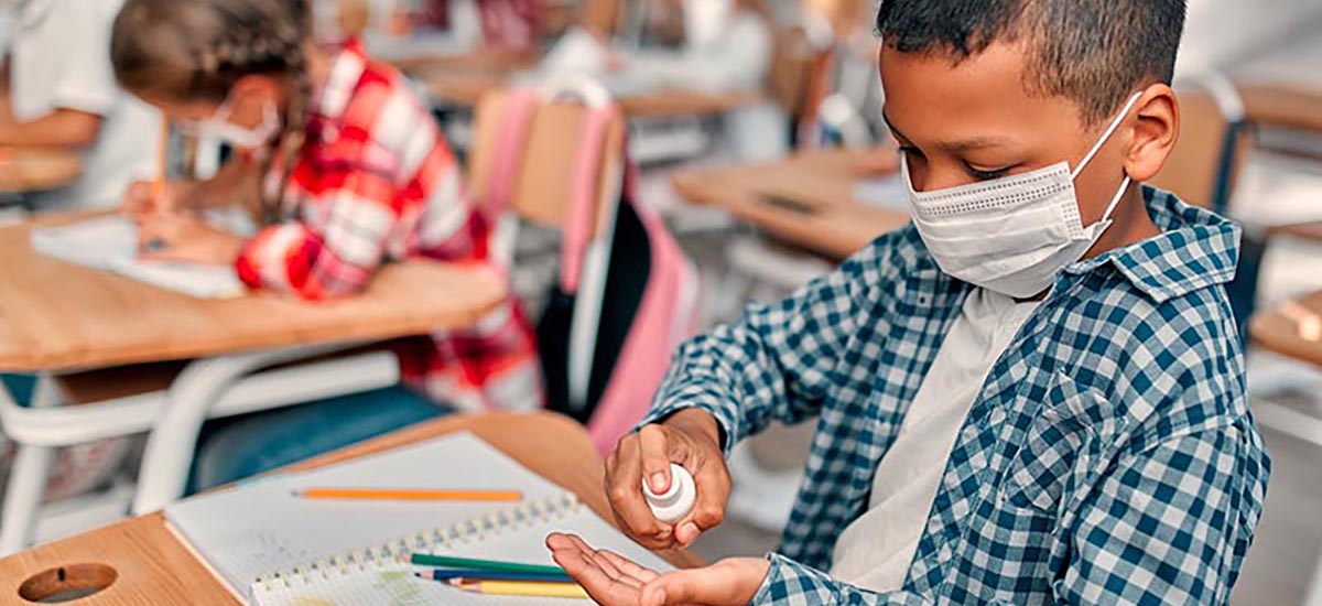 Student using hand sanitizer with mask