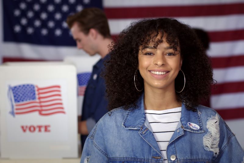 photo of young woman voting and smiling